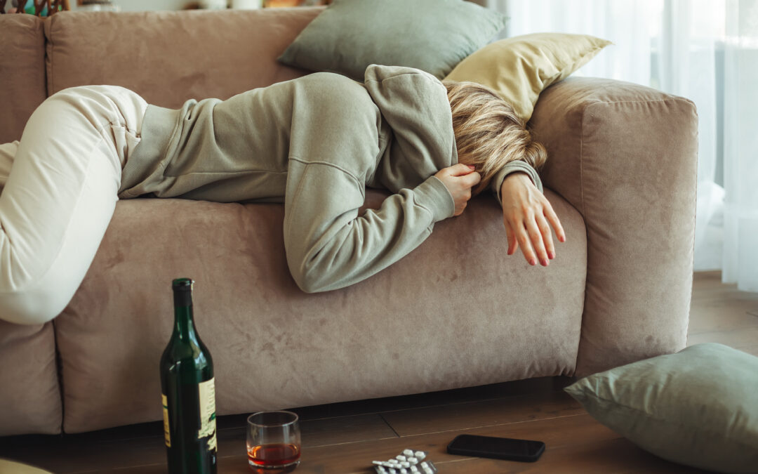 A woman lying on a sofa recovering from a hangover.